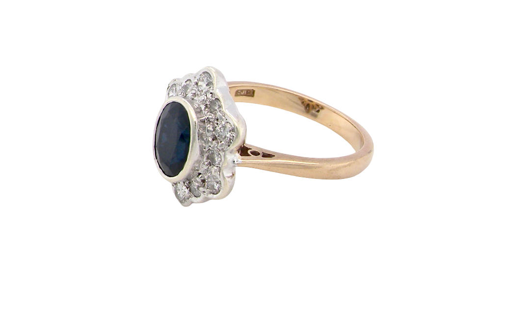 side A 9 carat gold cluster ring that features an inky black blue oval cut sapphire. This measures 8x6mm in a safe rim style setting