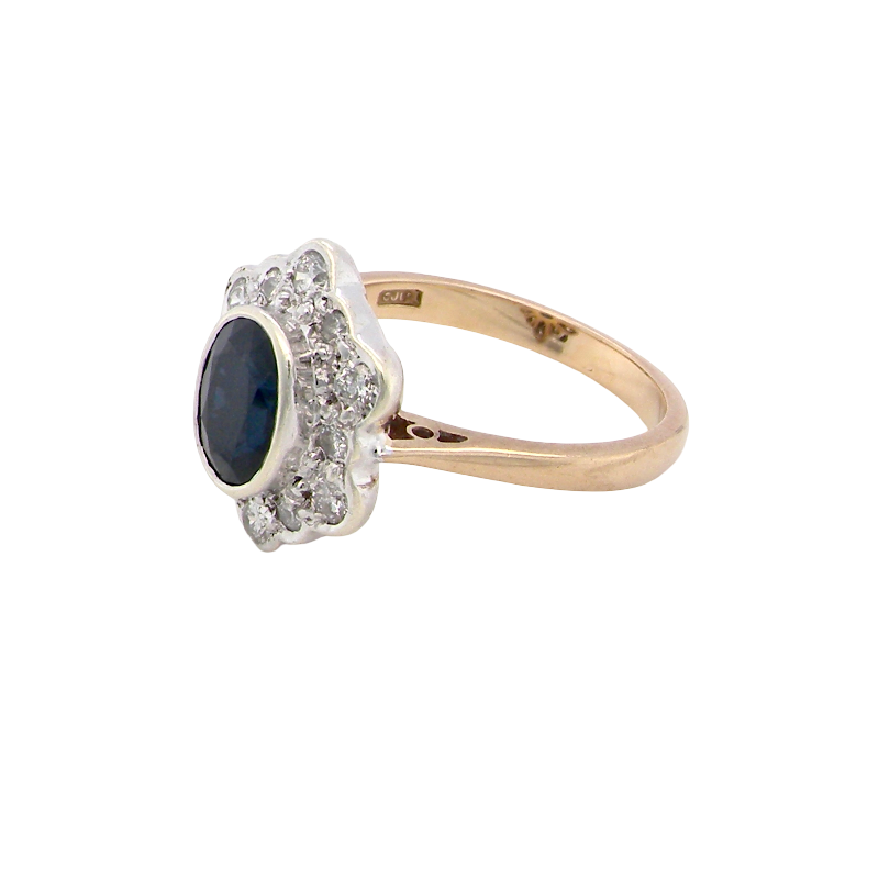 side A 9 carat gold cluster ring that features an inky black blue oval cut sapphire. This measures 8x6mm in a safe rim style setting