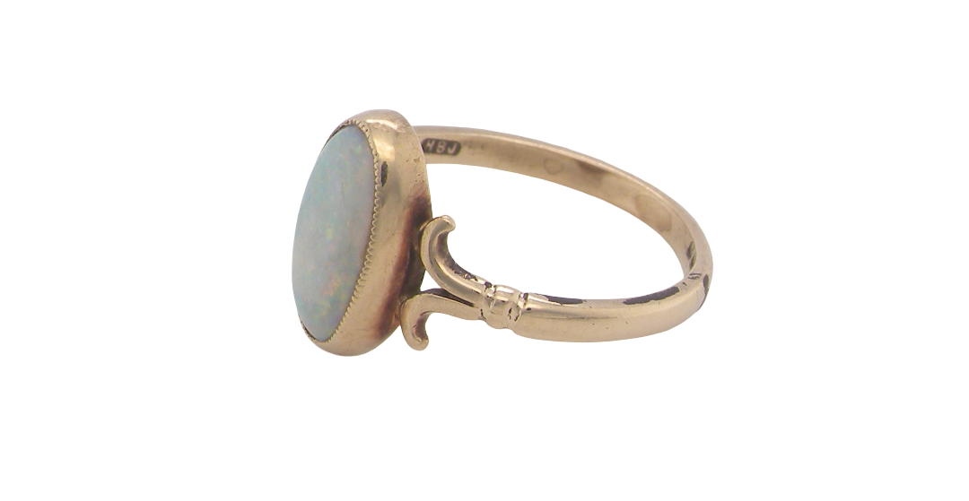 side A 9 carat gold dress ring that features an oval shaped opal. Measures 12x6.7mm, with a very good play of colour across the white background. Mille grain setting