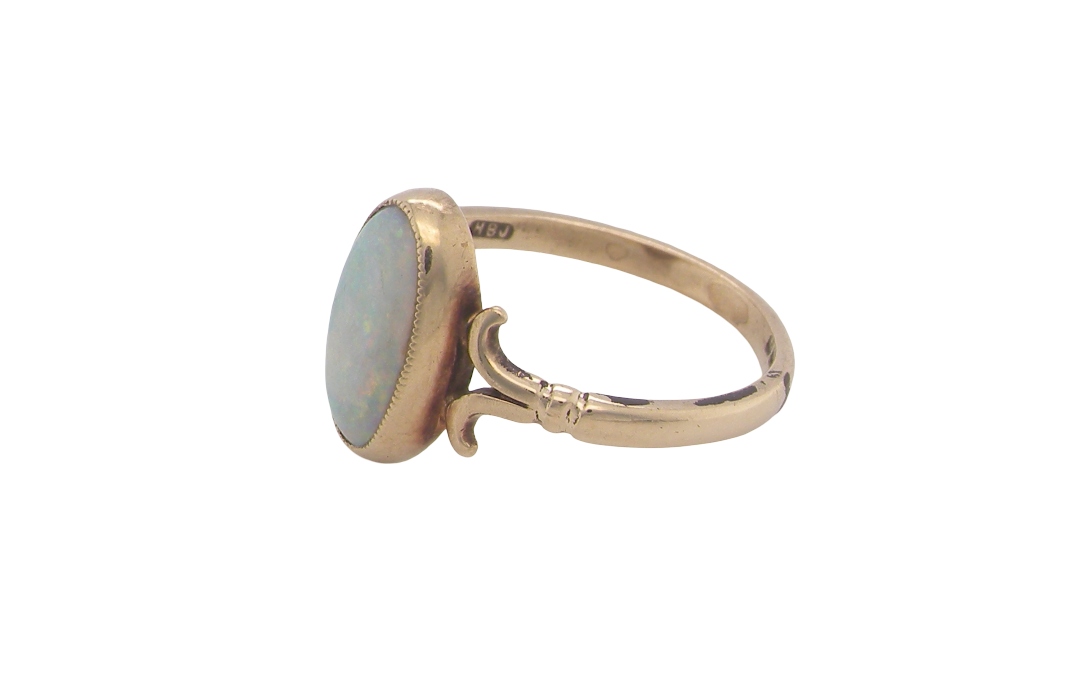 side A 9 carat gold dress ring that features an oval shaped opal. Measures 12x6.7mm, with a very good play of colour across the white background. Mille grain setting