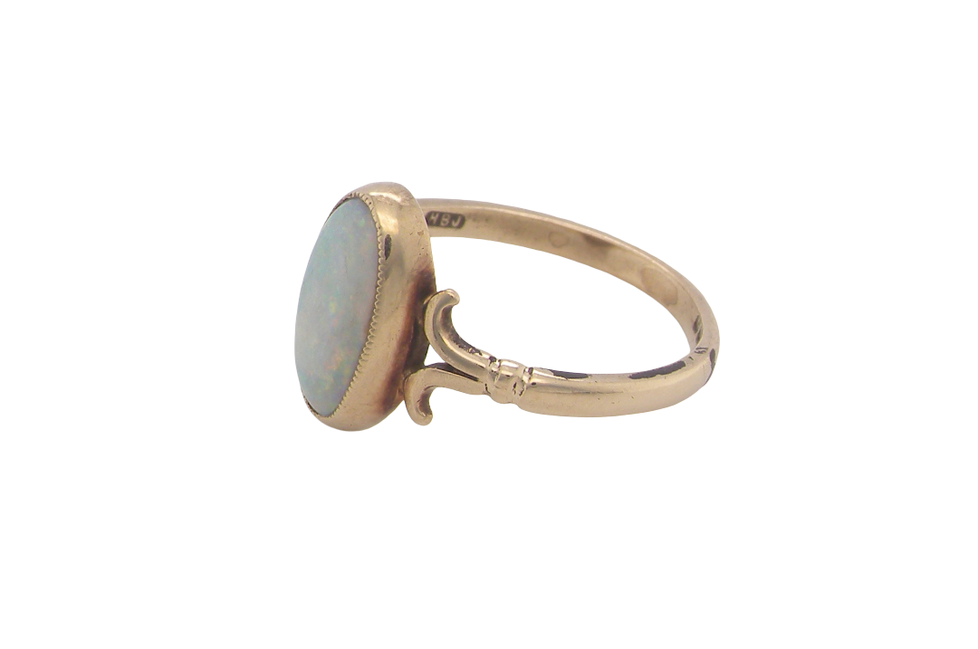 side A 9 carat gold dress ring that features an oval shaped opal. Measures 12x6.7mm, with a very good play of colour across the white background. Mille grain setting