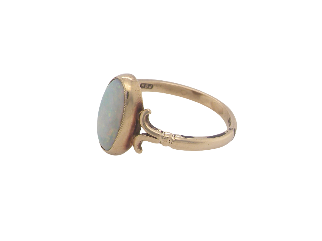 side A 9 carat gold dress ring that features an oval shaped opal. Measures 12x6.7mm, with a very good play of colour across the white background. Mille grain setting
