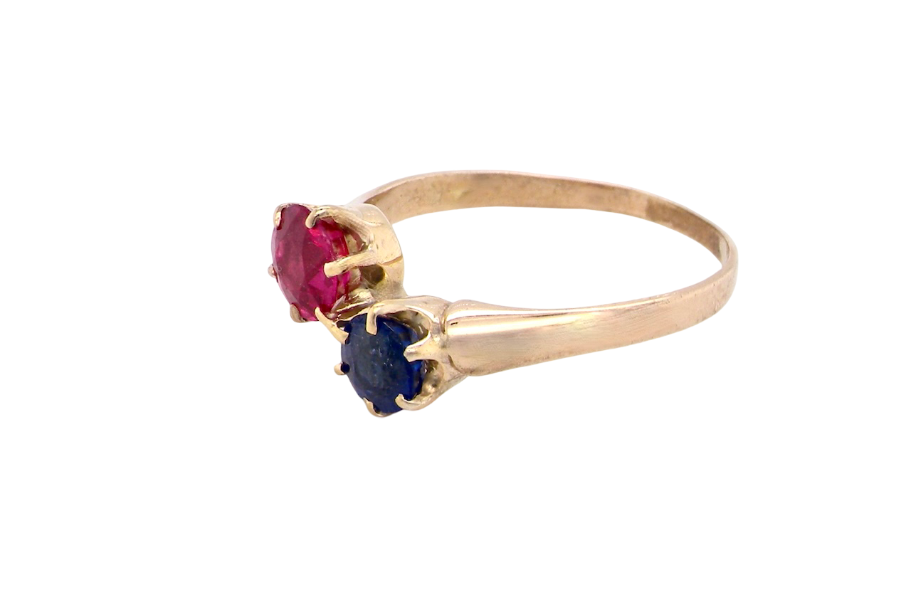 Gold ring with red and blue gemstones on a white background