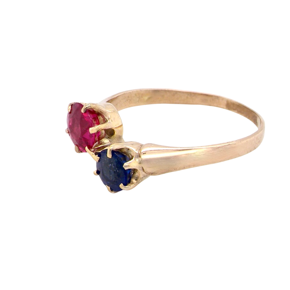 Gold ring with red and blue gemstones on a white background