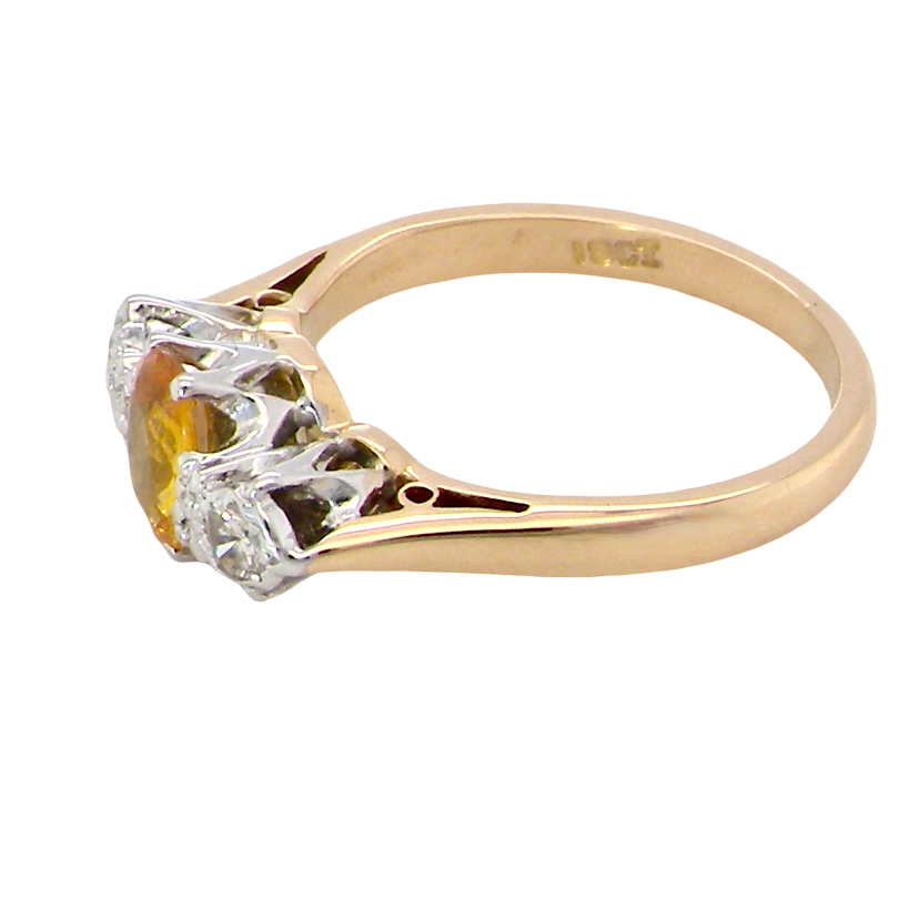 A yellow gold ring with a three-stone setting featuring a central yellow gemstone and two clear accent stones, shown on a plain white background.