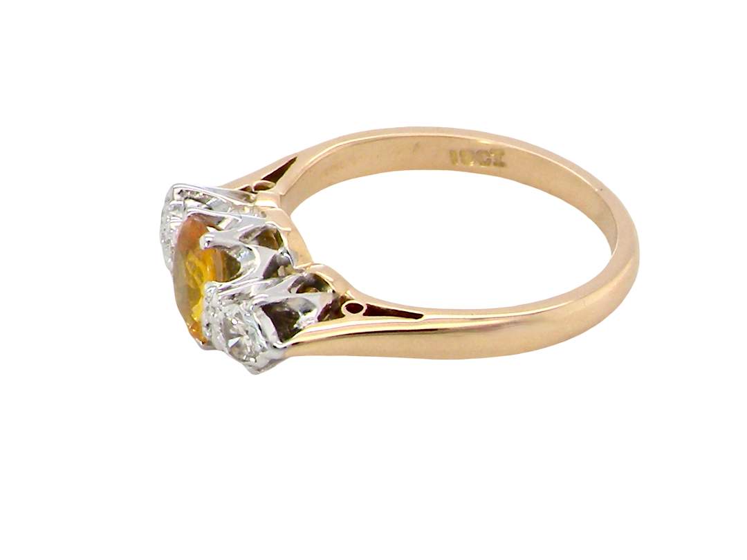 A yellow gold ring with a three-stone setting featuring a central yellow gemstone and two clear accent stones, shown on a plain white background.