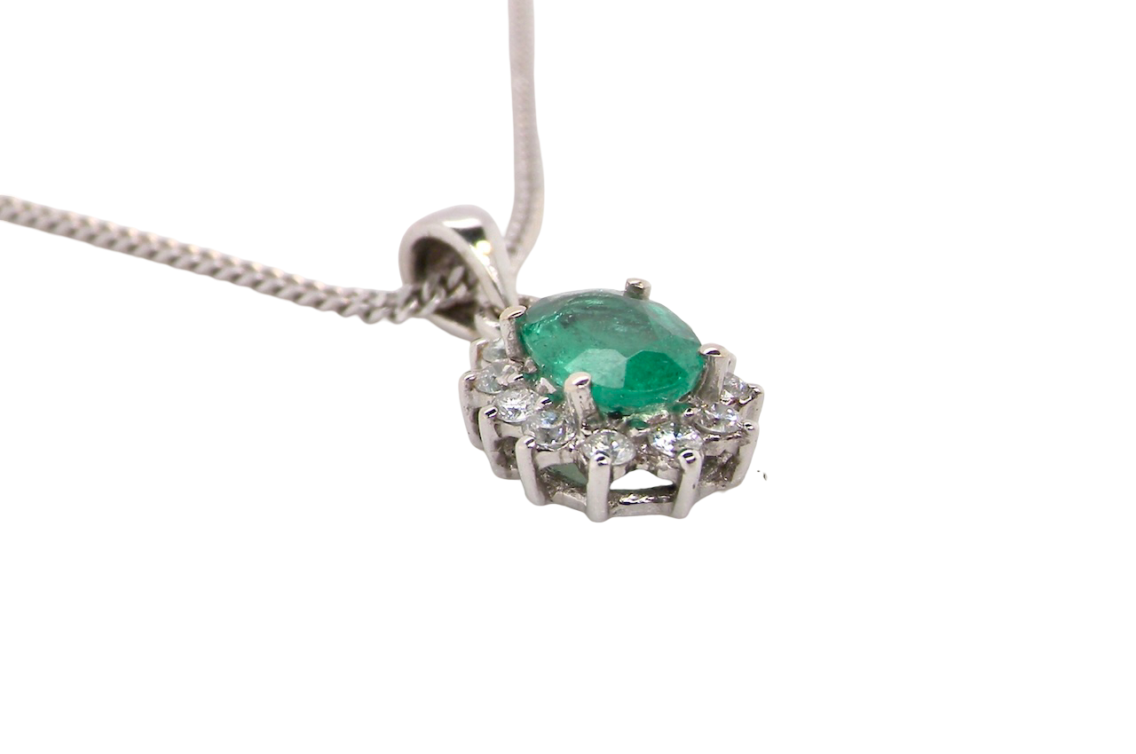 side A beautiful traditional cluster pendant featuring a vibrant oval-cut emerald