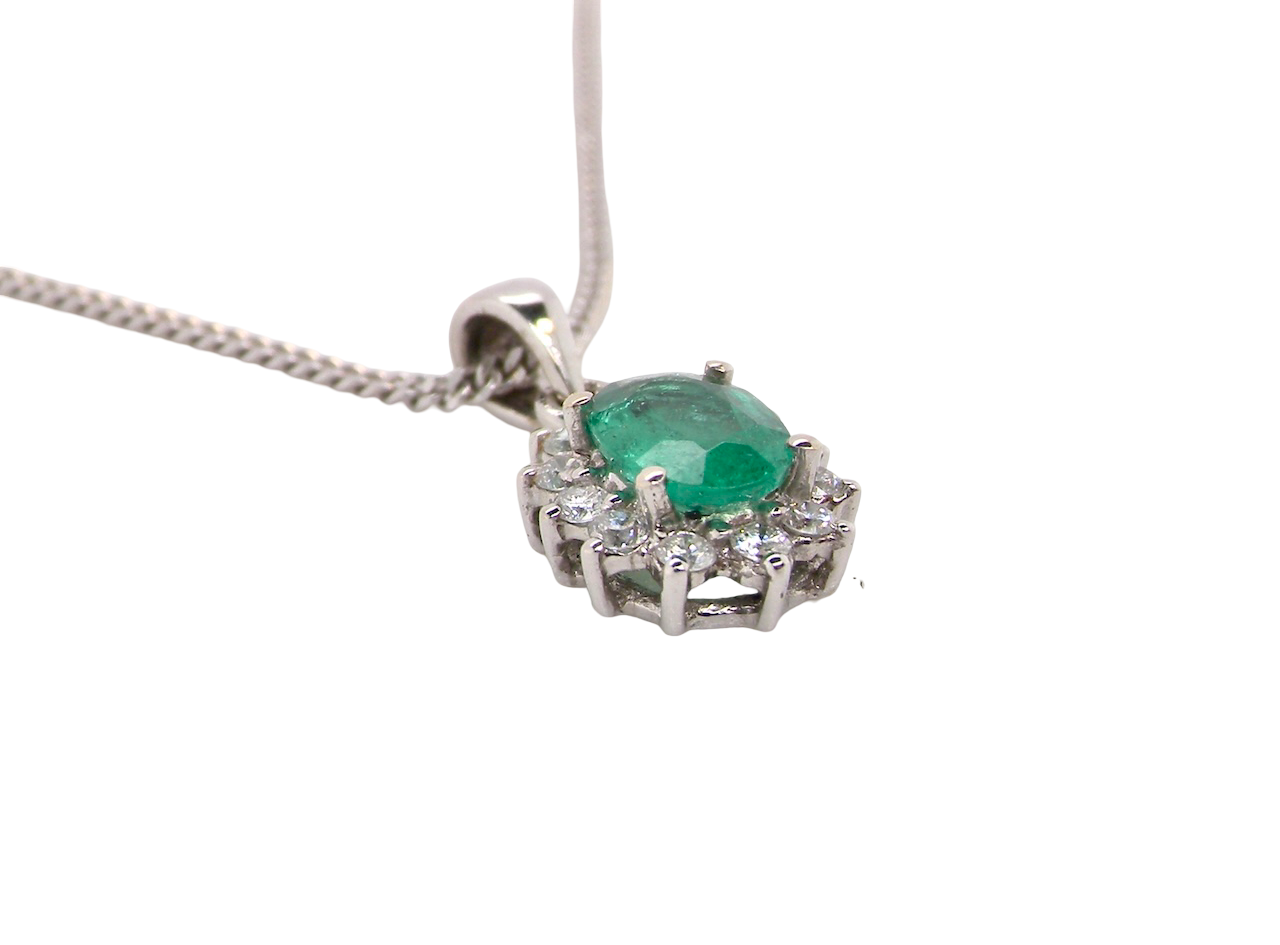 side A beautiful traditional cluster pendant featuring a vibrant oval-cut emerald
