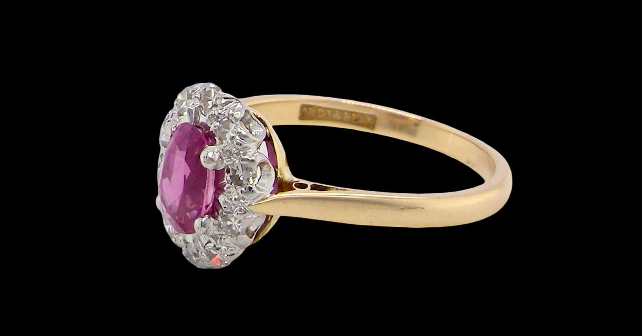 side A beautiful vintage cluster ring showcasing a vivid pink sapphire centre stone, measuring approximately 6.6 × 4.3 mm(estimated 0.65 carats).