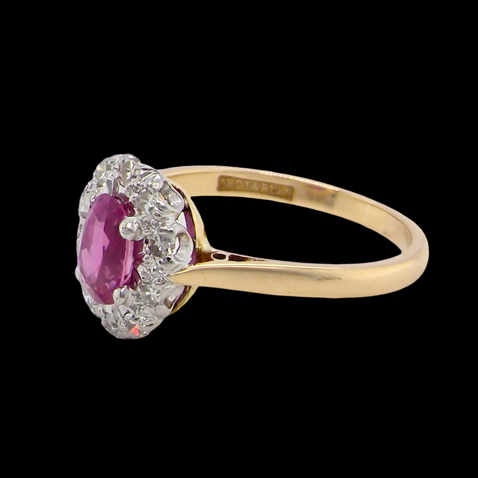 side A beautiful vintage cluster ring showcasing a vivid pink sapphire centre stone, measuring approximately 6.6 × 4.3 mm(estimated 0.65 carats).