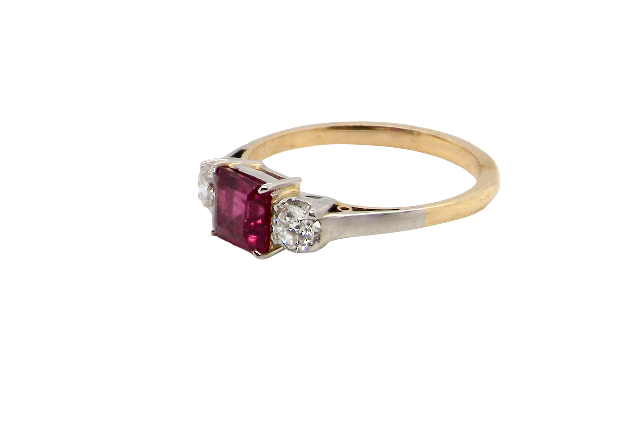 Gold ring with a red gemstone and diamond on a white background