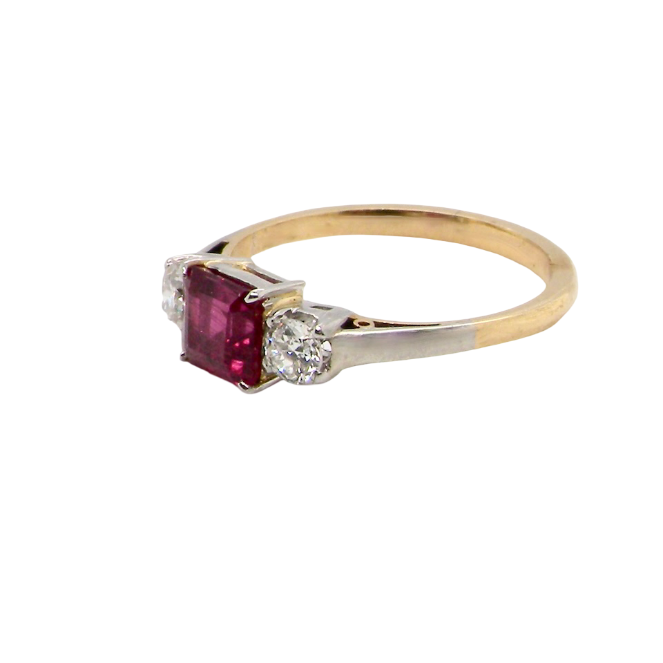 Gold ring with a red gemstone and diamond on a white background