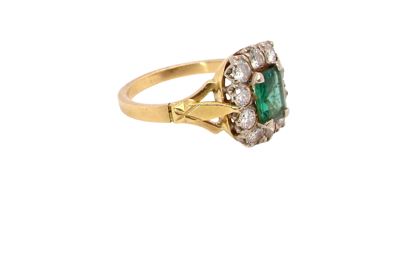 side A cluster ring that features a rectangular emerald centre stone, 7x5mm . Deep green colour, natural inclusions that can be seen under an eye glass, but not easily visible via the naked eye.