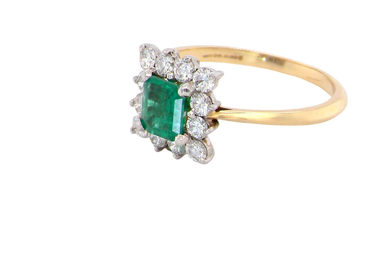 side A lcluster ring that features to the centre a rectangle shaped emerald, 7x5mm. Shows a deep grass green colour which does have natural inclusions common with most emeralds, but the depth of colour is impressive.