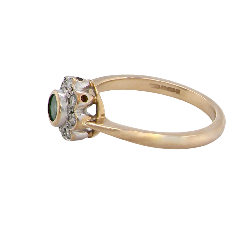 A vintage yellow gold ring with a cluster setting featuring a round green gemstone and small clear stones, shown on a plain white background.