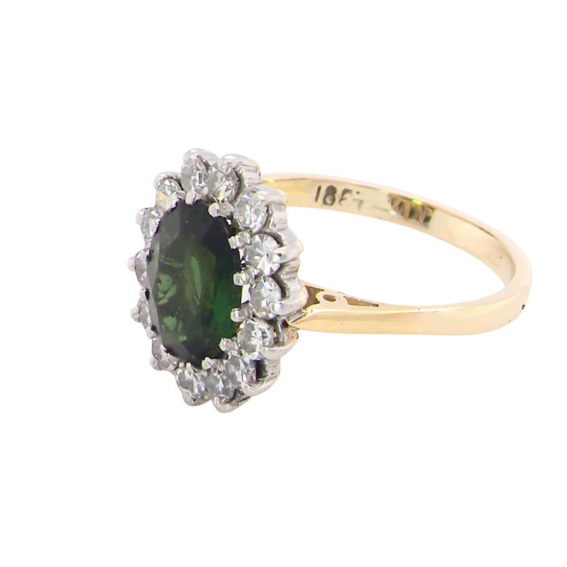 side A fine and impressive vintage cluster ring, centred with a striking oval-cut deep dark green tourmaline, measuring 9 x 7mm and estimated to weigh approximately 2.00 carats.