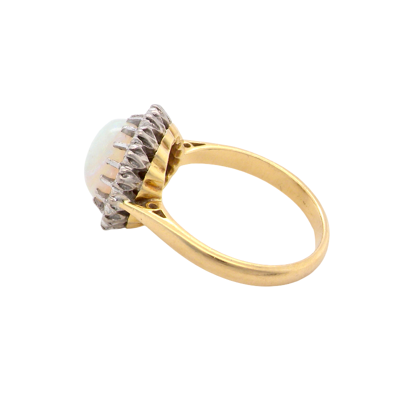 A yellow gold ring featuring a round white opal gemstone in a textured bezel setting with small clear accent stones, shown on a plain white background.