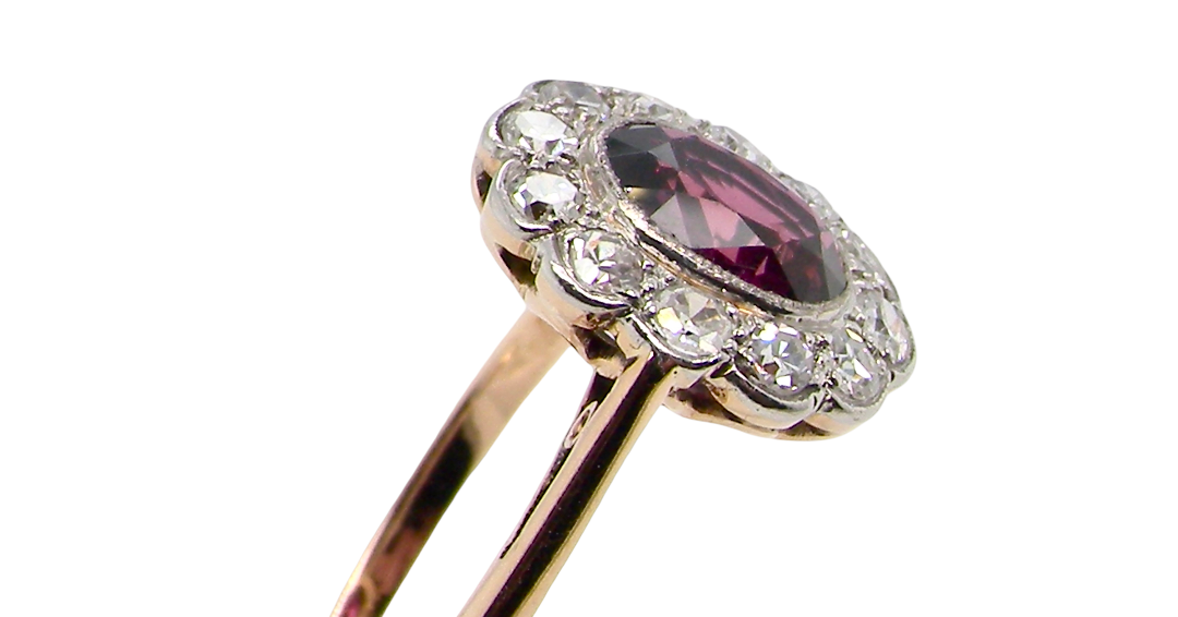 side A fine early 20th century cluster ring featuring to the centre an oval ruby, 6x5mm, deep burgundy red colour, mille grain setting. (est 1.02 carats)