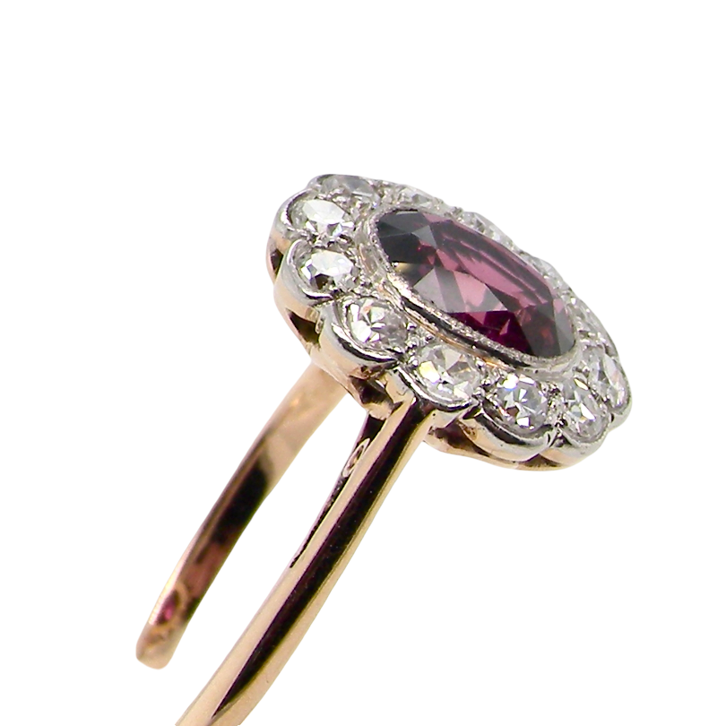 side A fine early 20th century cluster ring featuring to the centre an oval ruby, 6x5mm, deep burgundy red colour, mille grain setting. (est 1.02 carats)