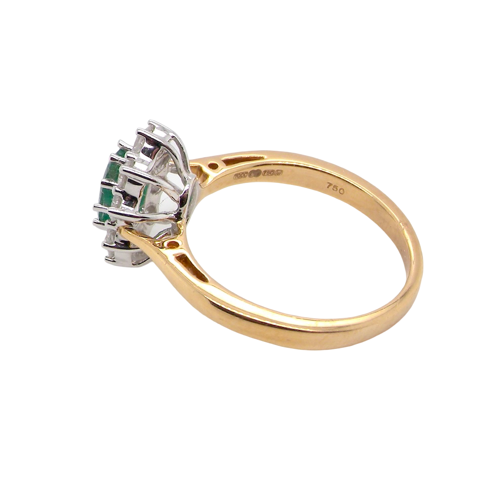 side A fine traditional emerald and diamond cluster ring, featuring a vibrant oval-cut emerald to the centre measuring approximately 7 × 5 mm