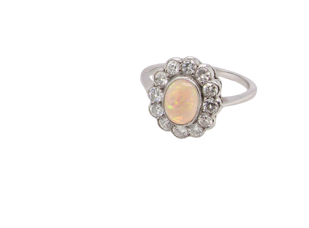side A fine vintage cluster ring. Features to the centre an oval shaped opal, with excellent play of colour, pink to one way, vibrant green to the other with flashes of electric blue also within the body of the gem.