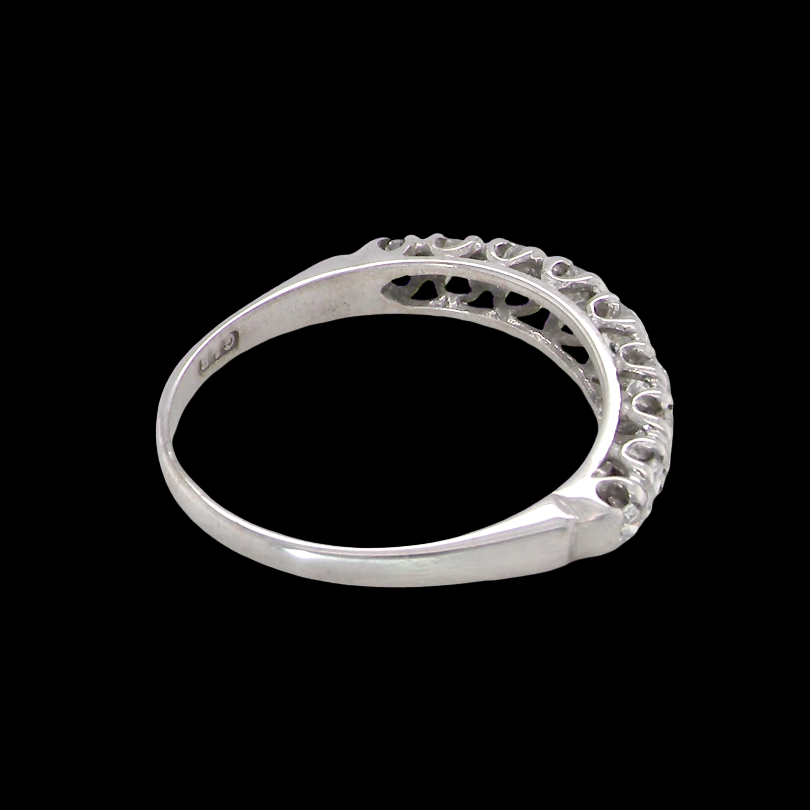 A ring with a curved, openwork filigree top featuring small clear stones, shown against a solid black background.