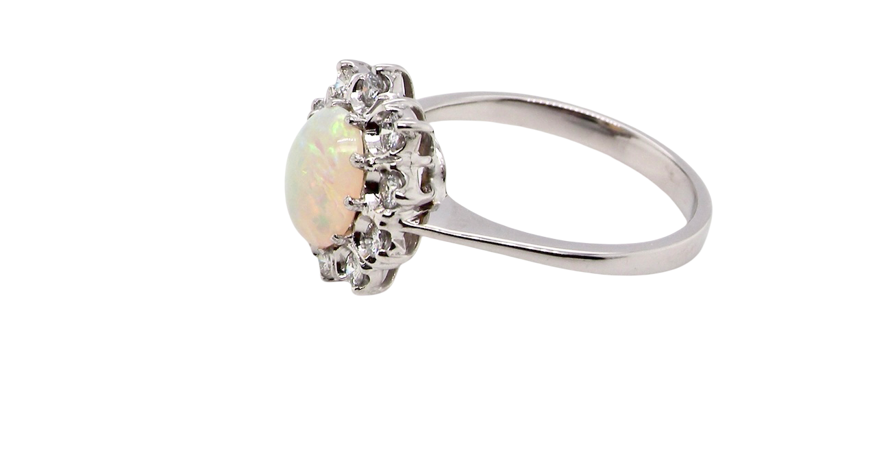 side A lovely white gold cluster ring. Features to the centre an oval white opal, 9x7mm, with an excellent play of colour.