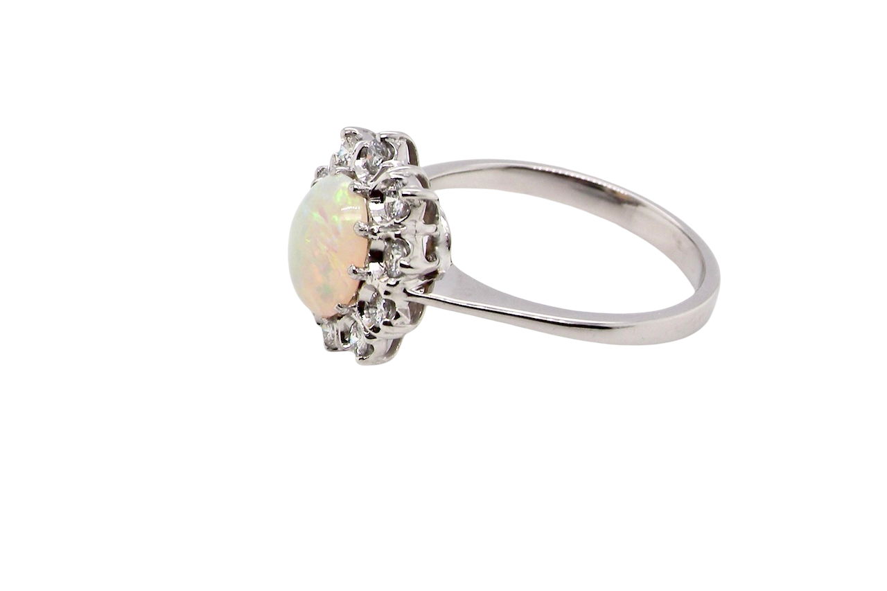 side A lovely white gold cluster ring. Features to the centre an oval white opal, 9x7mm, with an excellent play of colour.