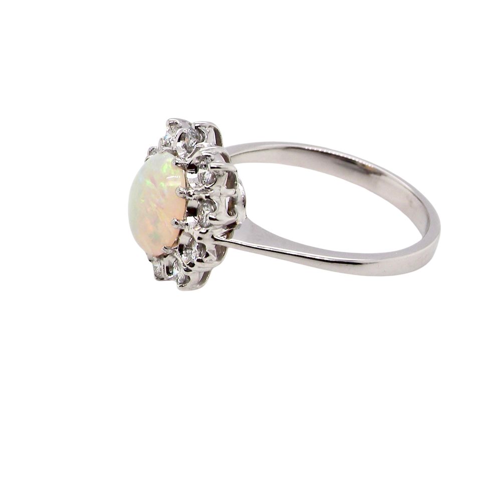 side A lovely white gold cluster ring. Features to the centre an oval white opal, 9x7mm, with an excellent play of colour.