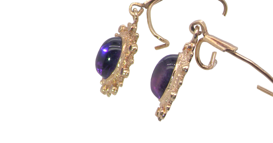 side A pair of drop earrings. Each set with a cabouchon cut amethyst 6x4mm and set with an antique look border.