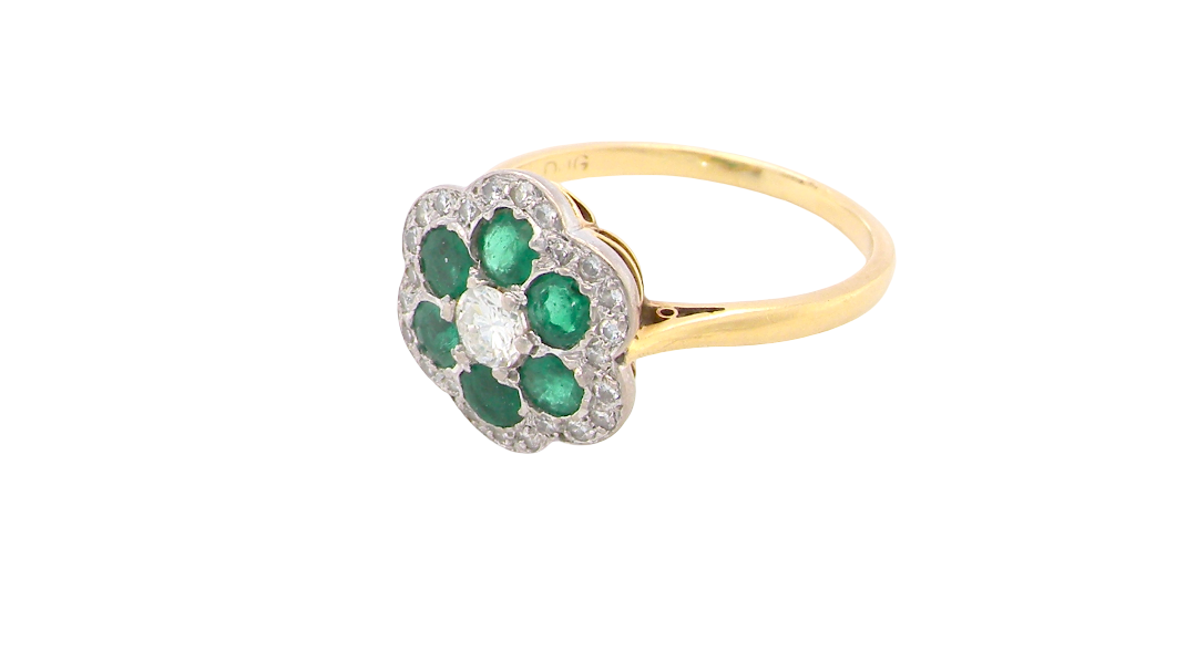 side A pretty cluster ring. Features emeralds and diamonds. Centre stone a brilliant cut white diamond, measures 4mm (0.25 carats). 