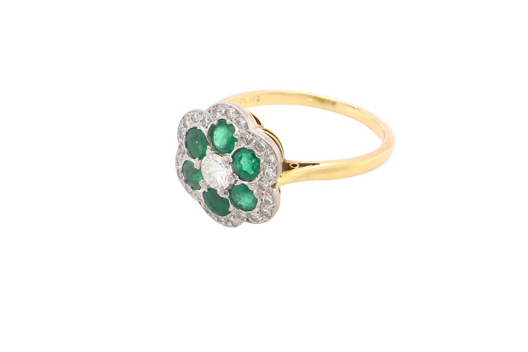 side A pretty cluster ring. Features emeralds and diamonds. Centre stone a brilliant cut white diamond, measures 4mm (0.25 carats). 