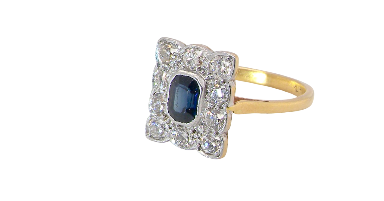 side A rectangular cluster ring that features in its centre a cushion shaped dark blue sapphire, that measures 5x3.5mm (est 0.30 carats)