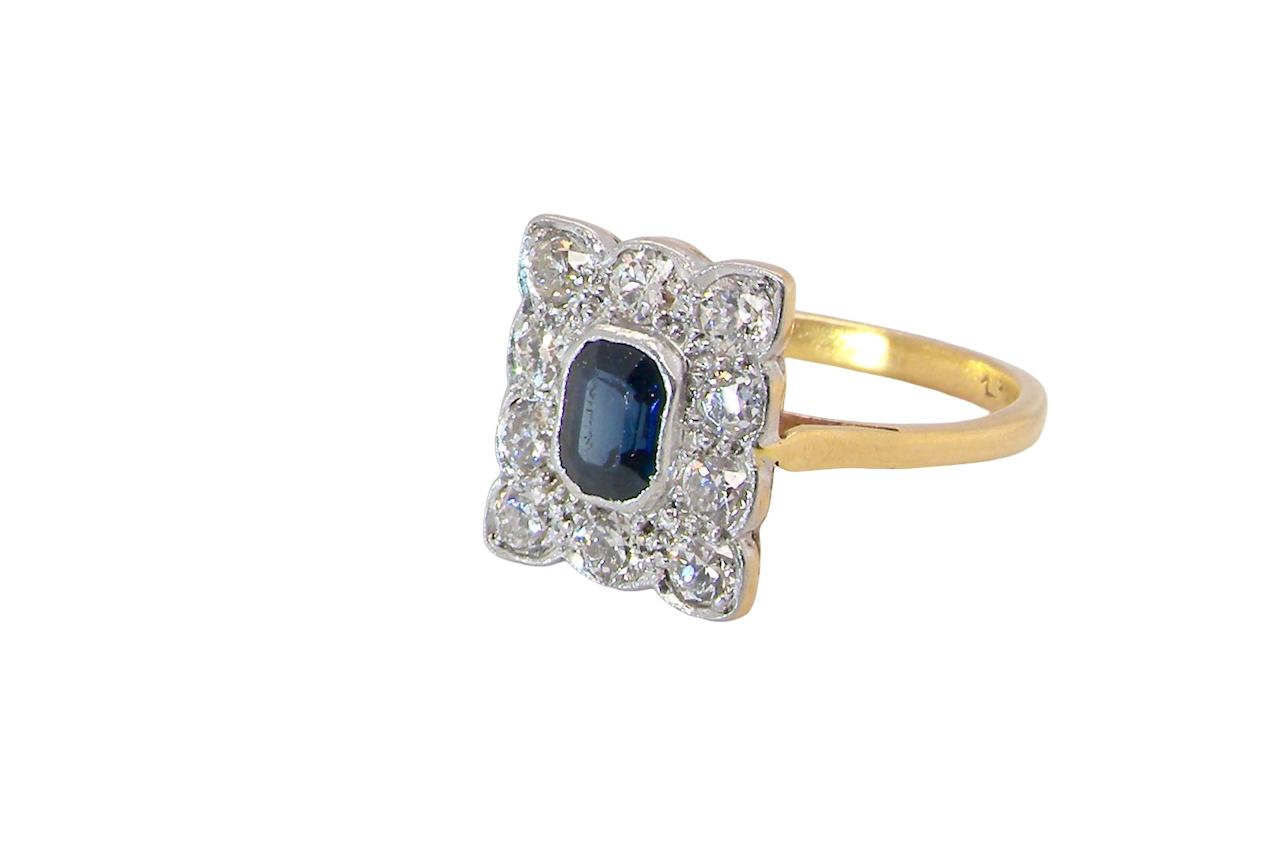 side A rectangular cluster ring that features in its centre a cushion shaped dark blue sapphire, that measures 5x3.5mm (est 0.30 carats)