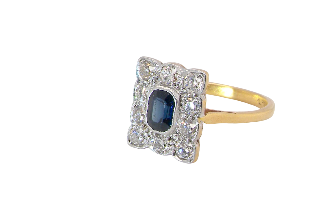 side A rectangular cluster ring that features in its centre a cushion shaped dark blue sapphire, that measures 5x3.5mm (est 0.30 carats)