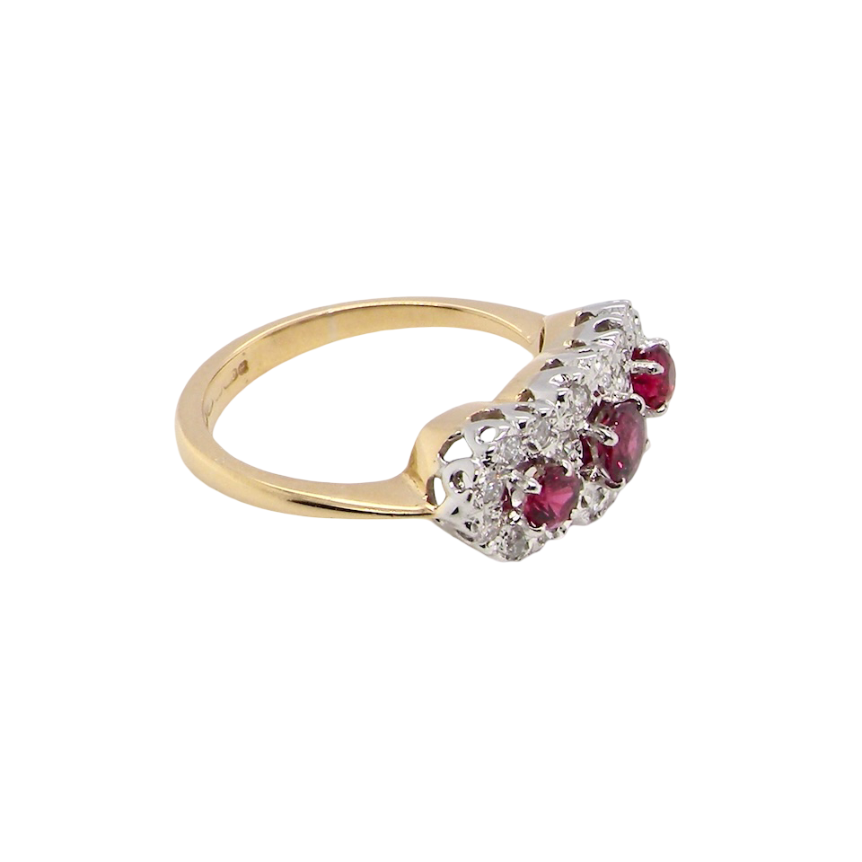 side A striking triple cluster ring crafted in 18 carat gold, dating circa 1990–2000, and fully hallmarked in the UK.
✨ Design & Gemstones
Three deep red rubies set to the centre of each cluster