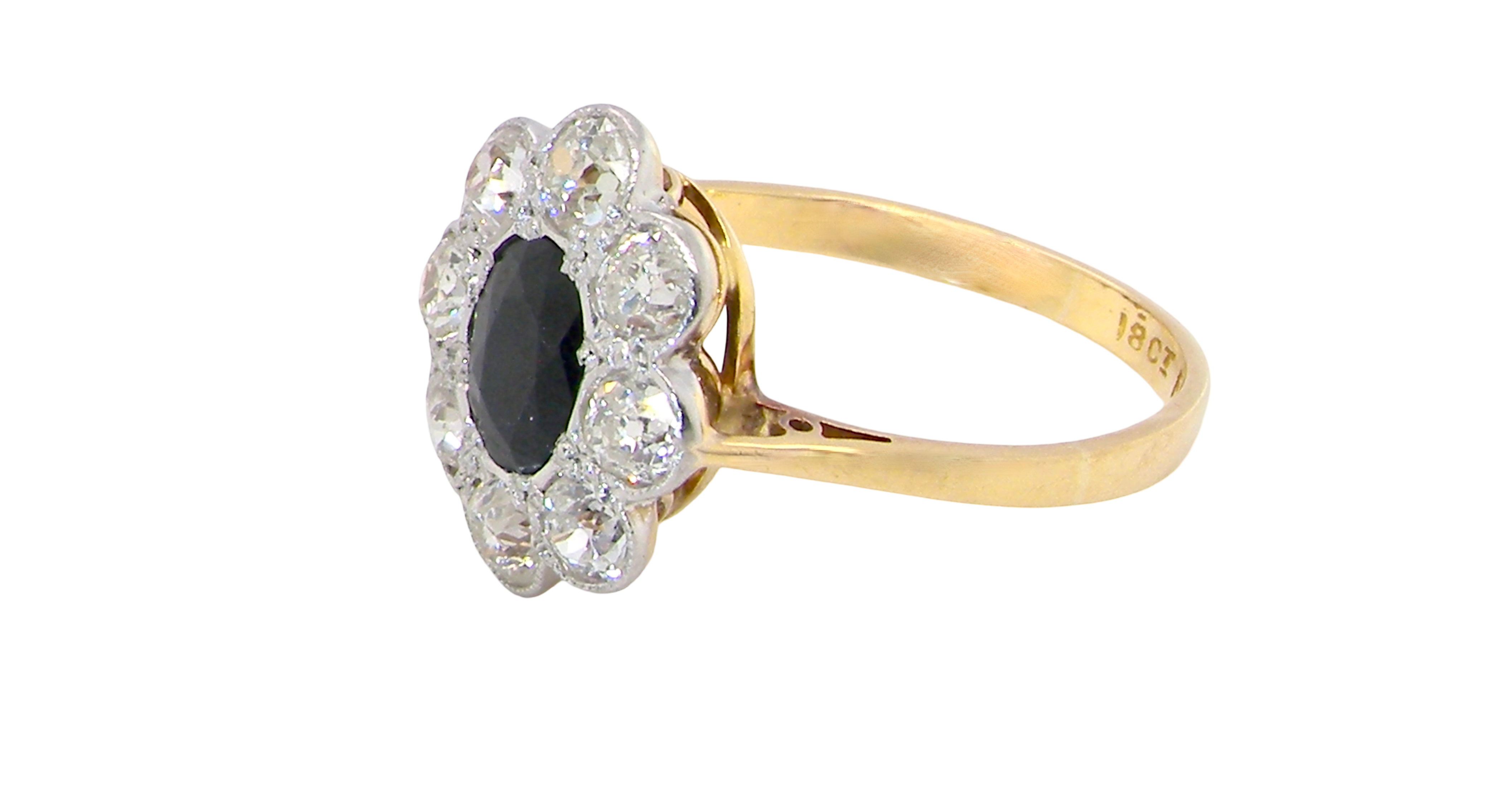 side A striking vintage sapphire and diamond cluster ring dating from the 1930s–1940s, beautifully crafted in platinum and 18 carat gold. At the centre sits a richly coloured oval-cut sapphire of deep inky blue-black hue, measuring approximately 7 x 5mm and estimated at 0.75 carats.