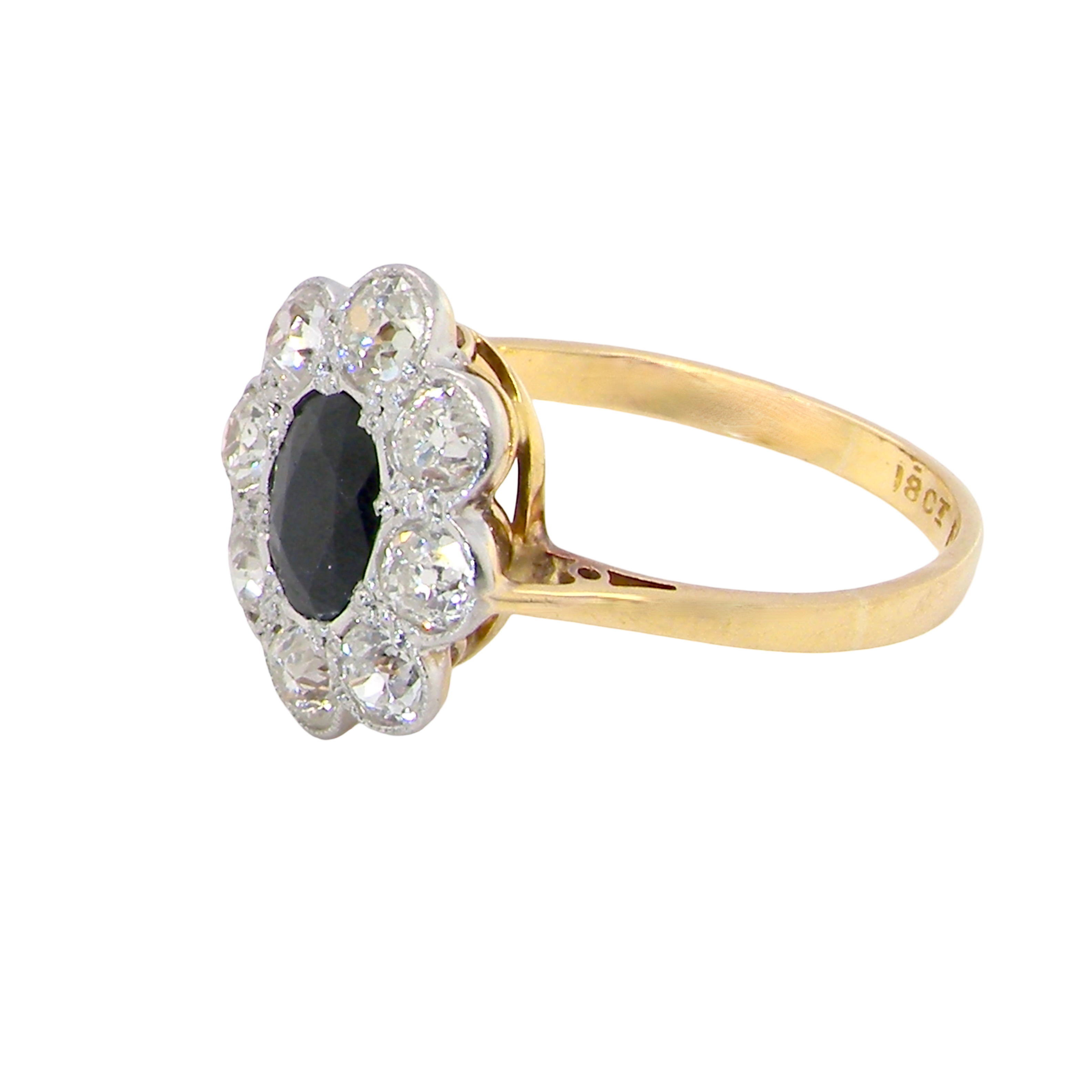 side A striking vintage sapphire and diamond cluster ring dating from the 1930s–1940s, beautifully crafted in platinum and 18 carat gold. At the centre sits a richly coloured oval-cut sapphire of deep inky blue-black hue, measuring approximately 7 x 5mm and estimated at 0.75 carats.