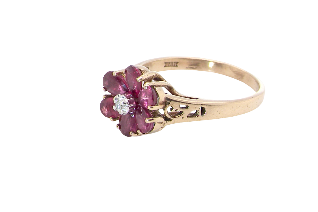 side A very pretty 9 carat gold cluster ring. The centre stone a small illusion set diamond, 1.3mm
Surrounded by six pear shaped raspberry red rubies,