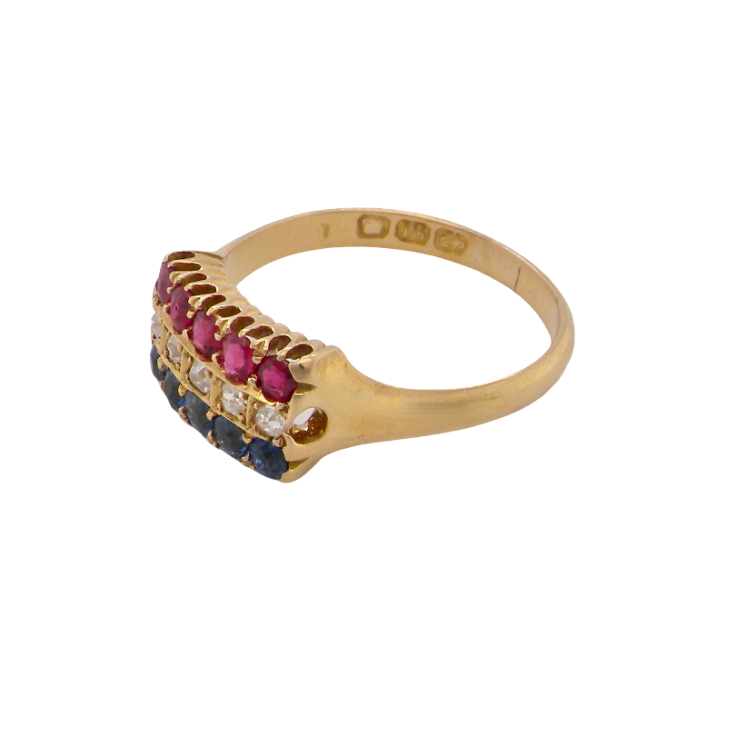 A vintage gold signet ring featuring a row of pinkish-red round stones, small clear stones, and dark blue round stones on a plain white background.