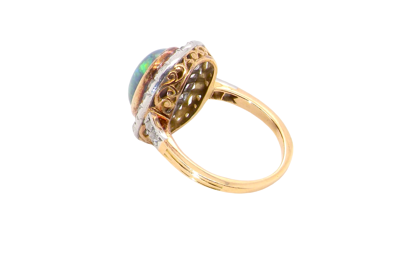 side A vintage early 20th century cluster ring. Features to the centre a black opal doublet, with an excellent play of colour, measures 9.5x7.5mm, in a rim setting.
