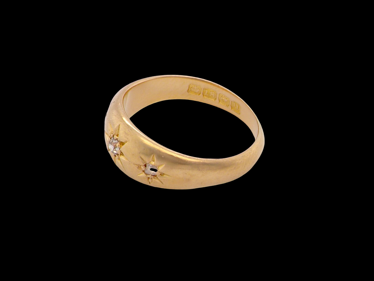 Gold ring with engraved design on a black background