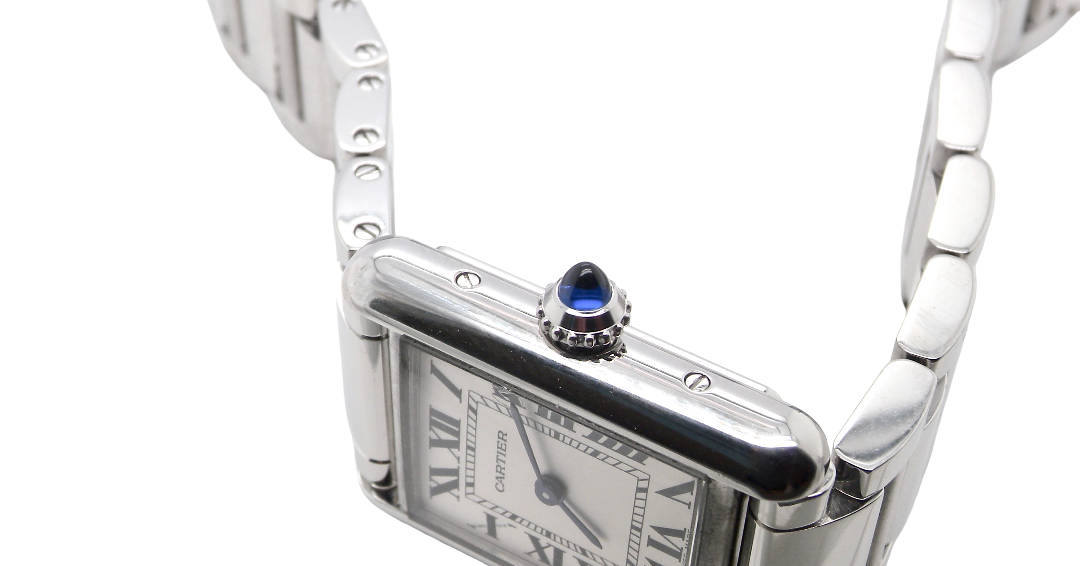 side A womans stainless steel Cartier Tank Must wrist watch. Model number WSTA0051.
Silver coloured dial with Roman Numerals. Blue steeled hands. Case measures 29.5x22mm, case thickness 6.6mm. Quartz movement, synthetic sapphire button.