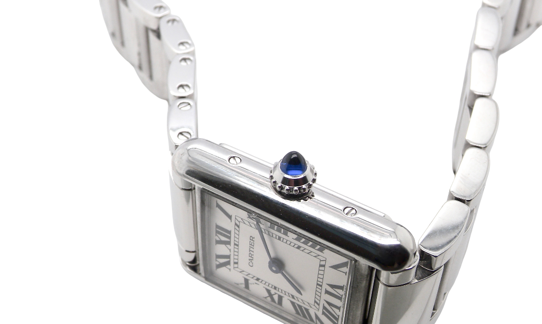 side A womans stainless steel Cartier Tank Must wrist watch. Model number WSTA0051.
Silver coloured dial with Roman Numerals. Blue steeled hands. Case measures 29.5x22mm, case thickness 6.6mm. Quartz movement, synthetic sapphire button.
