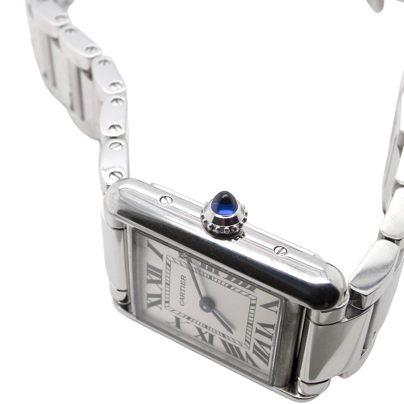 side A womans stainless steel Cartier Tank Must wrist watch. Model number WSTA0051.
Silver coloured dial with Roman Numerals. Blue steeled hands. Case measures 29.5x22mm, case thickness 6.6mm. Quartz movement, synthetic sapphire button.