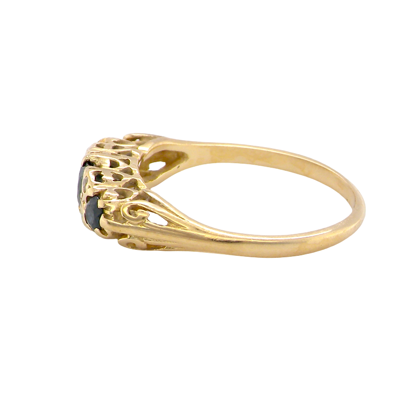 side An 18 carat* boat shaped ring. Features three dark inky blue sapphires, centre 4.7mm, each end a 3mm stone.