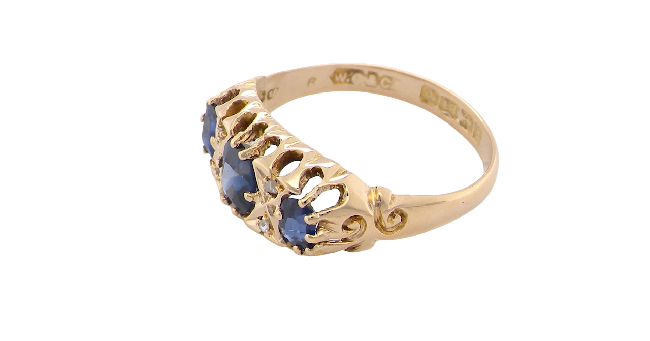 side An 18 carat gold antique boat shaped ring. Features three oval to cushion cut sapphires, centre 6x5mm, each end 5x3mm. Mid to dark blue