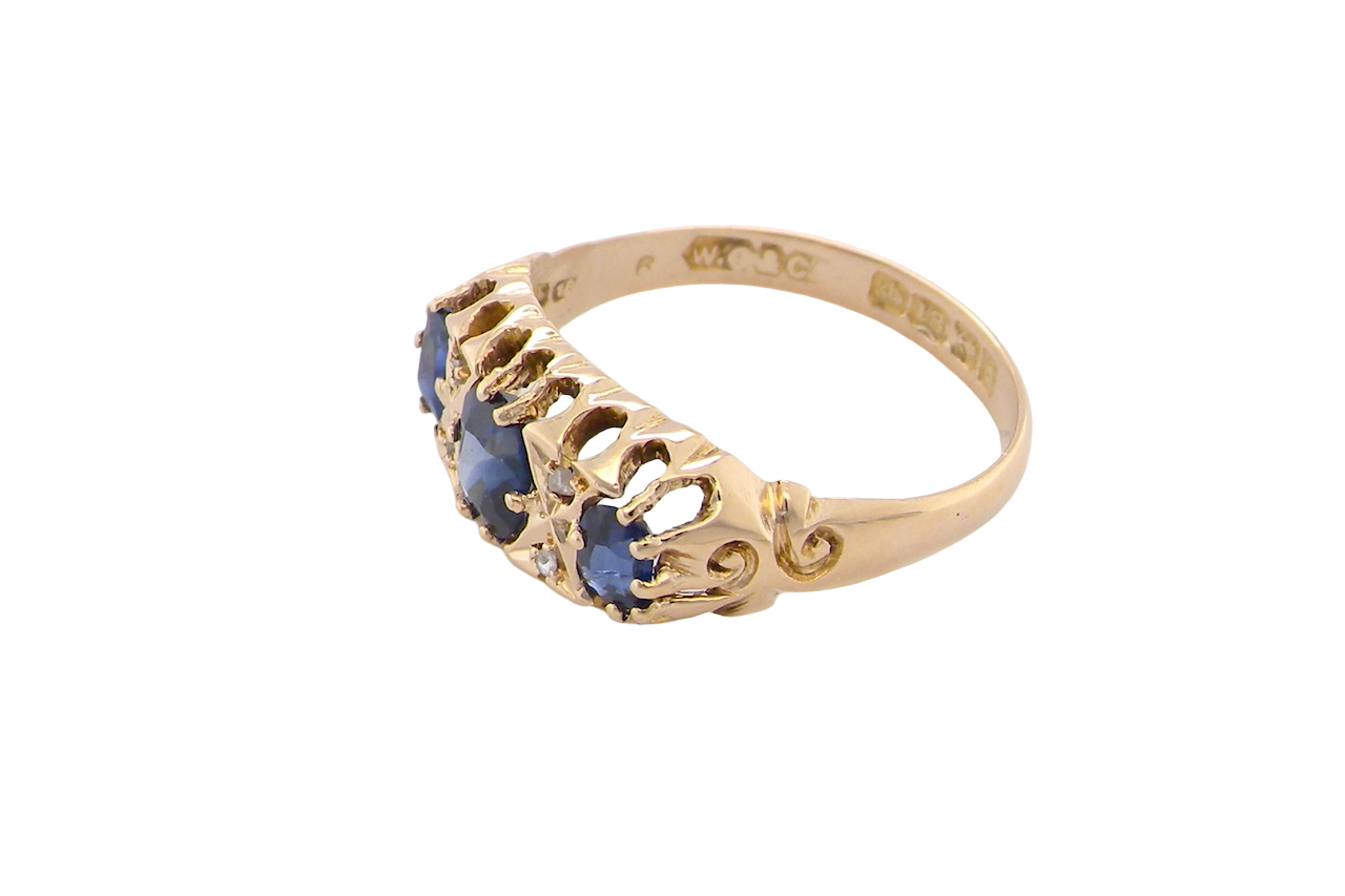 side An 18 carat gold antique boat shaped ring. Features three oval to cushion cut sapphires, centre 6x5mm, each end 5x3mm. Mid to dark blue