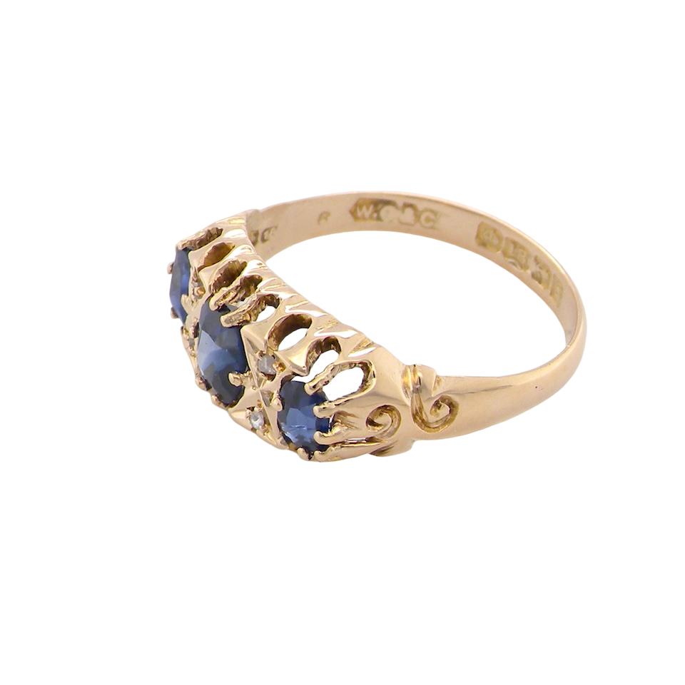 side An 18 carat gold antique boat shaped ring. Features three oval to cushion cut sapphires, centre 6x5mm, each end 5x3mm. Mid to dark blue