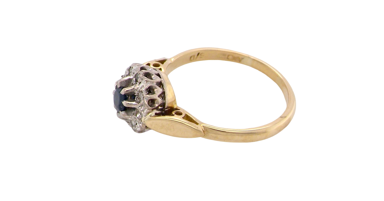 side An 18 carat gold cluster ring, features to the centre a dark blue sapphire, 3.6mm diameter. Claw set.